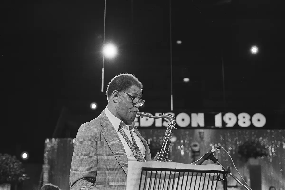 Dexter Gordon toca el saxo tenor davant d’un faristol, amb un rètol lluminós darrere